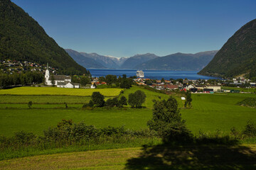 Fototapeta na wymiar Blick auf ein Kreuzfahrtschiff im Sognefjord mit dem Ort Vik im Vordergrund, Norwegen