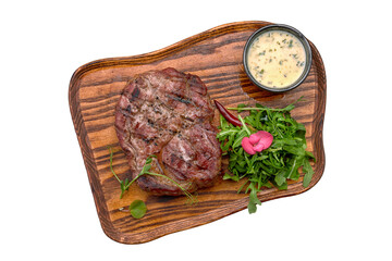 Pork steak with sauce and arugula, on a wooden board