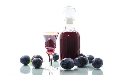 plum red wine in a glass and a decanter against the background of ripe large plums