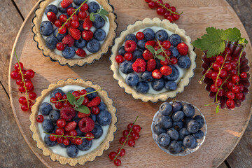 mixed berries tartlets on  wooden table, top view