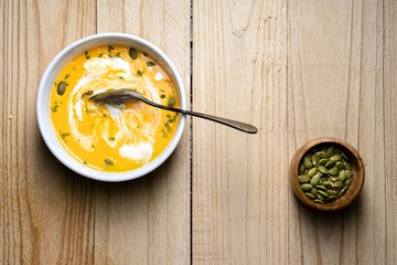 Stirred Yellow Pumpkin Soup on wooden background. Top view. Copy space.