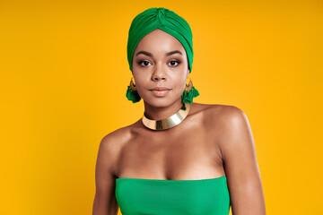 Beautiful African woman in traditional headwear standing against yellow background
