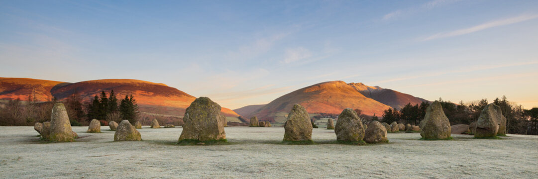Panoramic view of ancient stone circle on a cold winter morning with frosty grass in foreground. Castlerigg, Keswick, Lake District, UK.