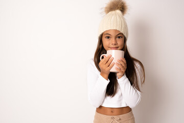A little girl holds a cup with a warm drink in the cold season. Winter clothes on the child.