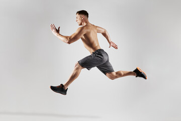 Confident muscular man with perfect body running against white background