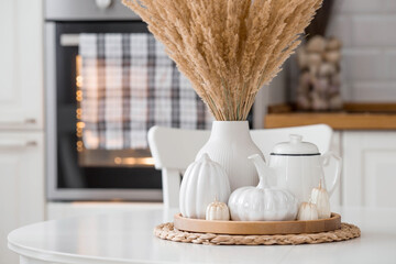 Still-life. Dried pampas grass in a vase, white ceramic pumpkins, a teapot and pumpkin-shaped...