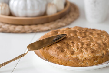 Still-life. Dried pampas grass in a vase, white ceramic pumpkins, candles and apple pie charlotte on a white table in the interior of a Scandinavian-style home kitchen. Cozy autumn concept.