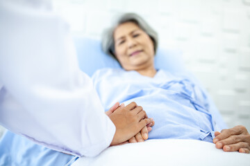 Asian doctor supporting and cheering up senior patient on bed in recover room. Healthcare and medicine concept.