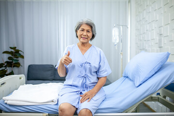 An elderly woman thumbs up and smiling in the recovery room. Healthcare and medicine concept.