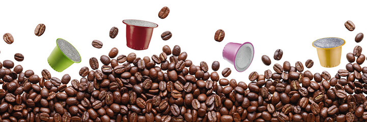 A pile of brown coffee beans lies, four colored capsules for a capsule coffee machine levitate...