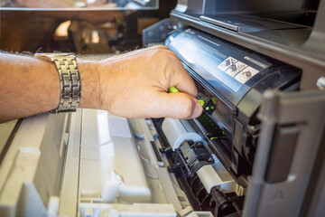 a man changes a cartridge on a laser printer
