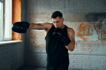 Confident young man practicing in punching while standing in gym