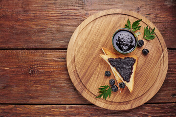 Top view of blackberry jam-stained sandwich toast bread and blackberry berries on a wooden background