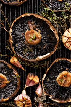 Grilled portobello mushrooms with thyme and garlic on a grill plate, close up view