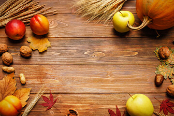 Autumn still life with pumpkin, apple, peach, wheat and barley ears, maple and oak leaves, walnuts and peanuts on a wooden background