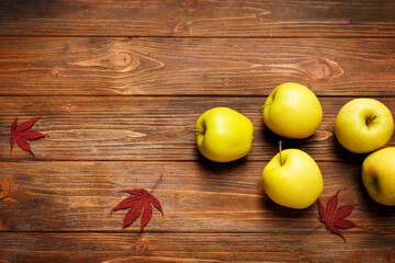Autumn still life with apple, peach, yellow leaves on a wooden background