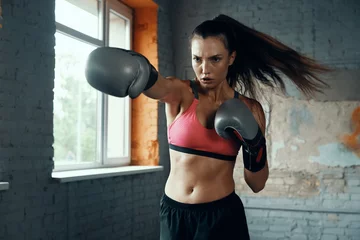 Tischdecke Beautiful young woman practicing her punch while standing in gym © gstockstudio