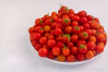 Red cherry tomatoes in a white dish on a light, minimalism