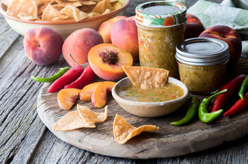 Peach and pepper salsa served with tortilla chips on a rustic board.