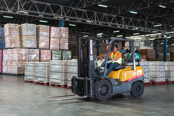 Asian male driver driving forklift to shipping delivery product in the warehouse distribution. import export logistic career, worker working at industrial factory. © winnievinzence