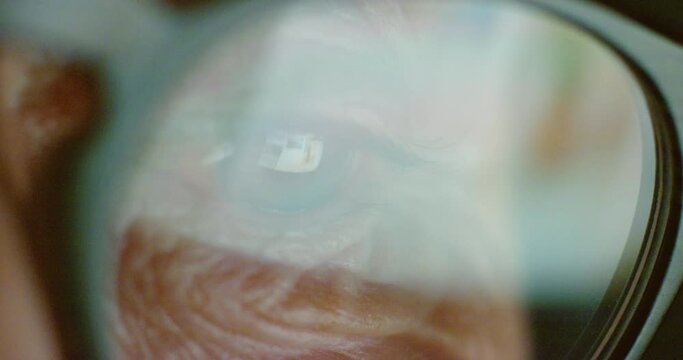 Elderly person with glasses, wrinkles around eye scrolling social media on phone or tablet. Senior, man or woman with spectacles, using smartphone or computer to browse the web in macro portrait.