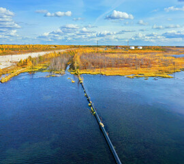Autumn industrial landscape. Western Siberia. Oil pipeline on water. Oil field.