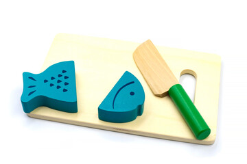 Wooden fish on magnets lies on a cutting board with a knife. Wooden toys for children