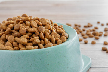 Dry food for cats and dogs in a green bowl on a wooden background.
