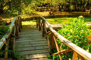 Wooden bridge over a stream in a natural park. Walking paths among ponds and streams