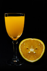 orange drink in glass cup on black background