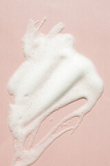 Facial foam texture from soap, face cleansing mousse bubbles on pink background