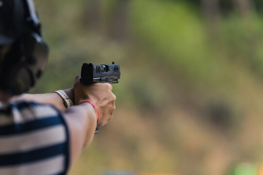 man practicing aiming with a gun at the shooting range, medium closeup blurred background. High quality photo