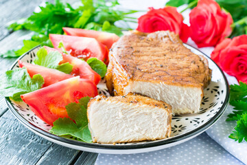 Steak of pork baked in the oven on a plate on a wooden background