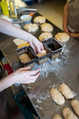 The process of making brioche in an artisan bakery. Laying the dough in the baking molds. Vertical photo.