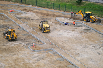 Working machines excavators and workers at construction site