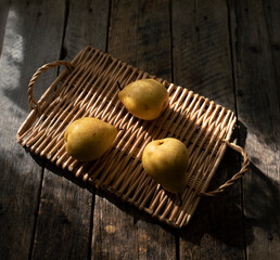 Still life with yellow pears on a wicker tray.