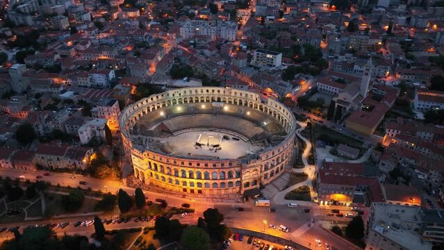 flying above historic city of Pula at night with evening illumination, historic Roman amphitheatre of Pula aerial view, tourism in Croatia, vacations in the Adriatic