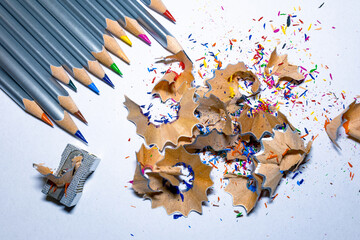 Sharpened pencils with shavings and a sharpener nearby