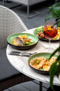 Food on the table summer terrace, grilled sea bass fillet and hummus.