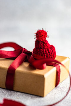 Close-up of a Christmas gift box tied with a ribbon and decorated with a miniature santa hat