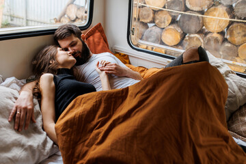 Young beautiful loving couple travelling across country in the van. Millennial man and woman in a travel camper. Cozy atmosphere, vacations vibe