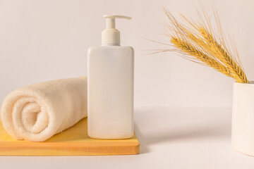 Shampoo bottle white towel white mug with ears of wheat.
