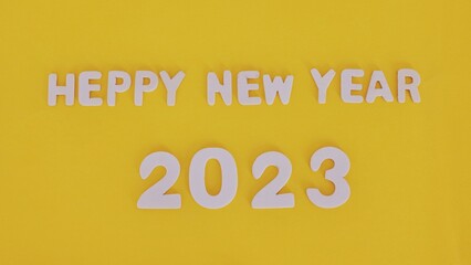2023 word is made of wooden blocks on the yellow background . Happy New Year. New year and holiday concept