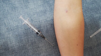 the syringe lies near the hand on a blue background