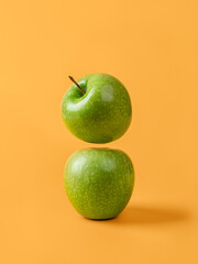 Two fresh green apples against yellow background. Organic ingredient for weight loss slimming diet. Raw juicy fruit for vitamin healthy eating. Antioxidant vegetarian snack.