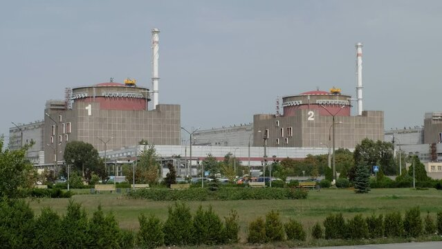 Power units of Zaporozhye NPP under cloudy sky in summer. Large territory of nuclear power plant with green trees and bushes in Energodar city