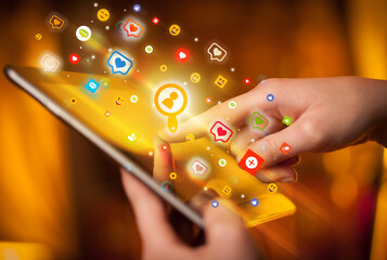 Close-up of a hand using tablet with social media icons
