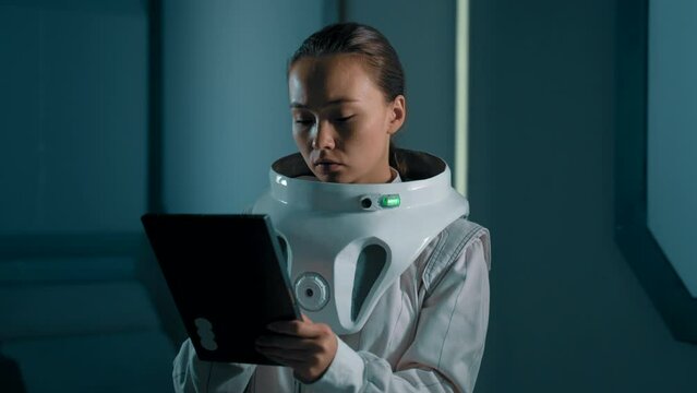 An astronaut woman works on a tablet in the interior of a spaceship. Research aboard the ISS. Making onboard records into a digital device in space