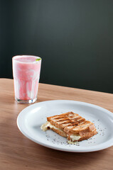 Misto-quente, ou torrada, com pão de fôrma e queijo muçarela acompanhado de um copo de vitamina feito com frutas vermelhas e yogurte natural