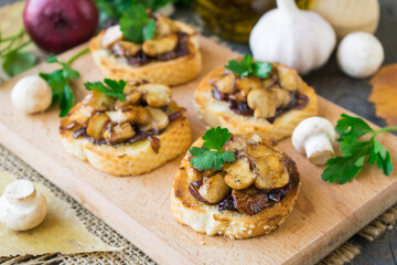 Italian bruschetta with champignons and caramelized red onions on a wooden background. Selective focus